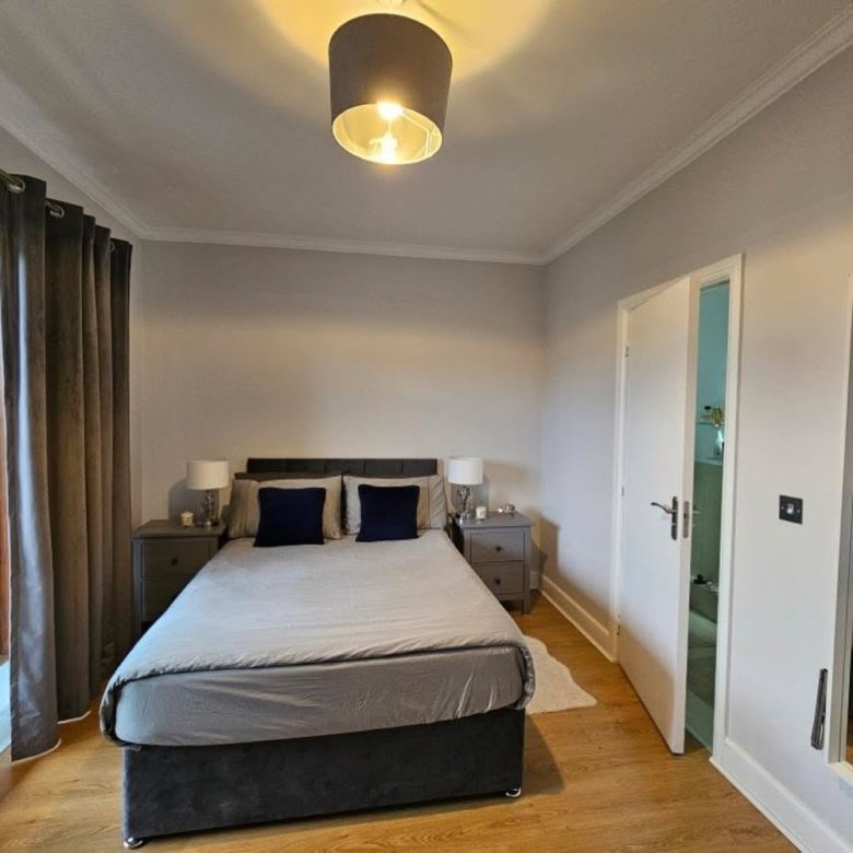 Cozy bedroom with gray bedding, bedside tables, and warm lighting. Modern interior design.