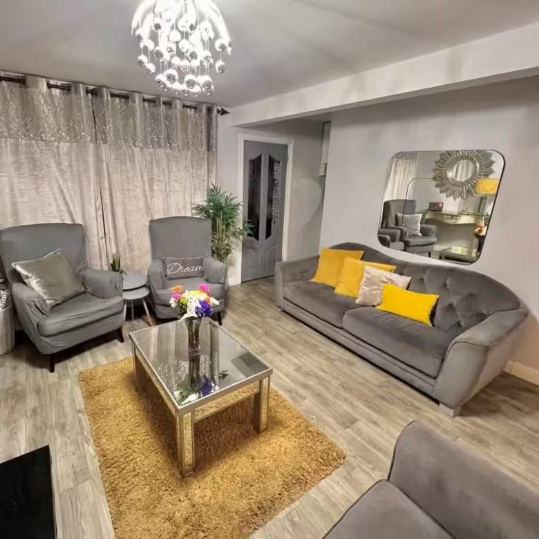 Stylish gray living room with velvet sofa, armchairs, and mirrored accents.