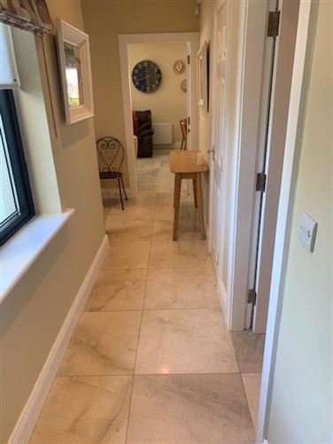 Hallway with tan tile floor, wall clock, console table, and doorway.