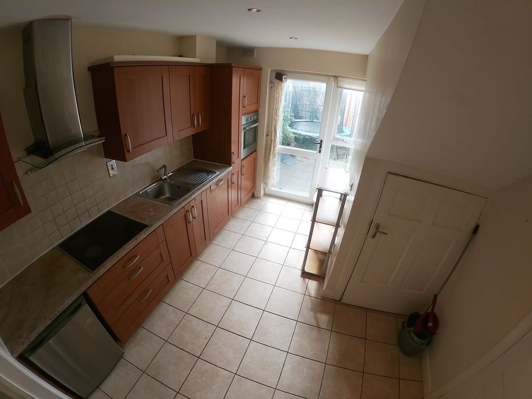 Kitchen with brown cabinets, stainless steel appliances, and door to backyard.
