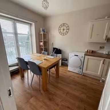 Bright kitchen with dining table, washing machine, and clock.