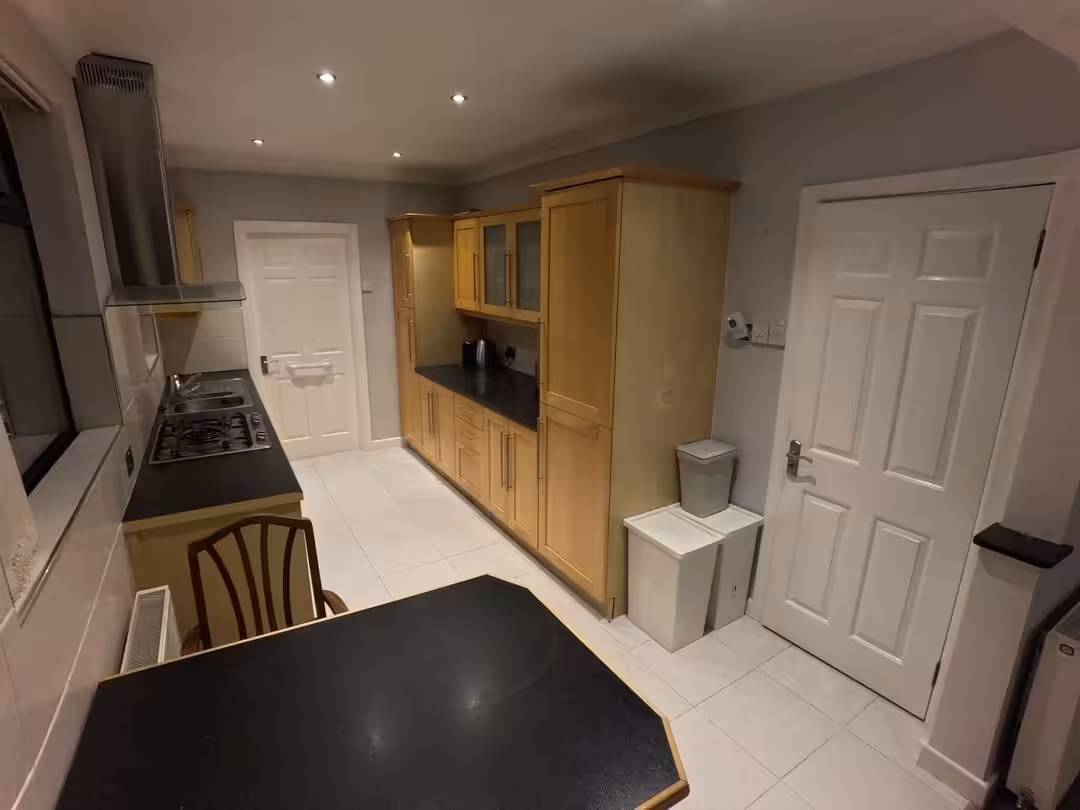 Kitchen interior with wooden cabinets, black countertops, and white door.