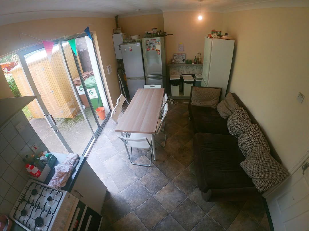 Cozy kitchen-living space with sofa, table, and kitchen appliances. Neutral color palette.