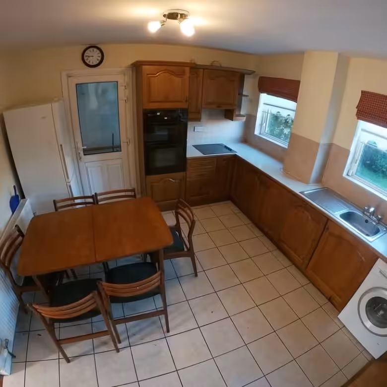 Kitchen with wood cabinets, dining table, white appliances, and tile floor.