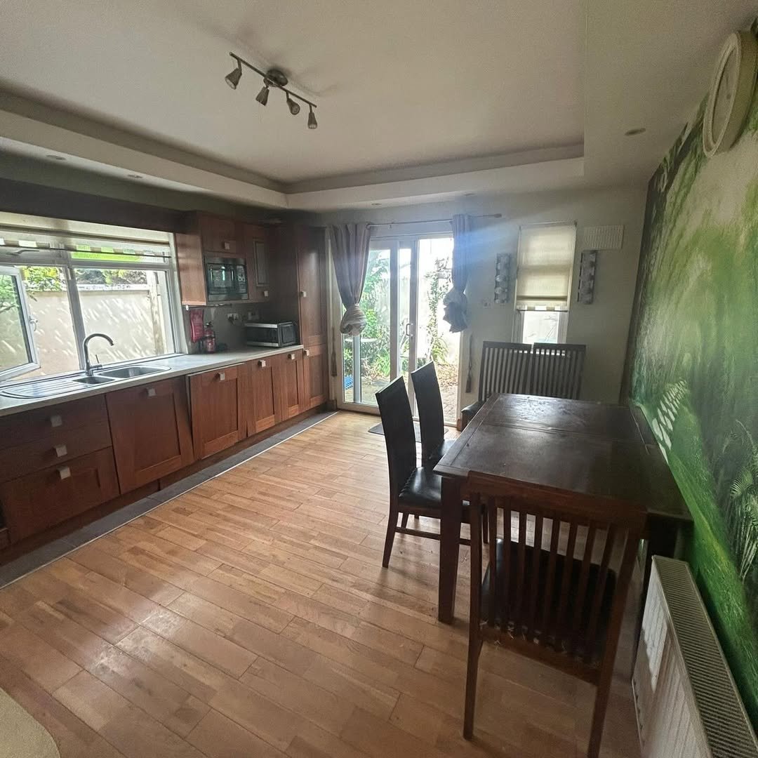 Kitchen with wood cabinets, dining table, chairs, and garden view.