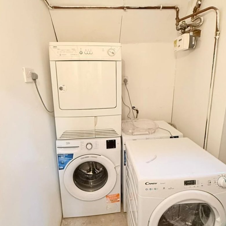 Stacked washer and dryer units, plus two additional washing machines in laundry room.