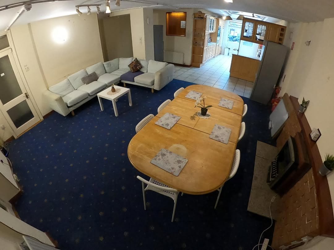 Living and dining room with blue carpet, large table, and sectional sofa.