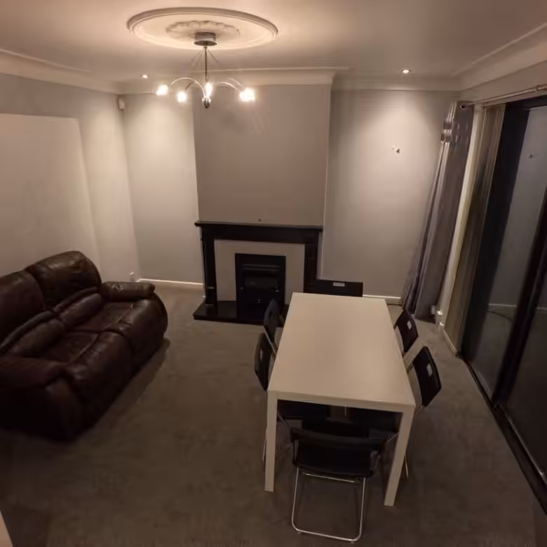 Living room with brown leather sofa, white table, and fireplace.