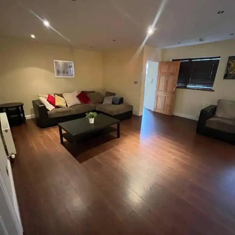 Living room with brown sofa, coffee table, and dark wood floors.