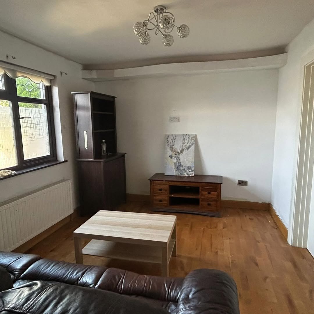 Living room interior with brown leather sofa, wooden furniture, and window.