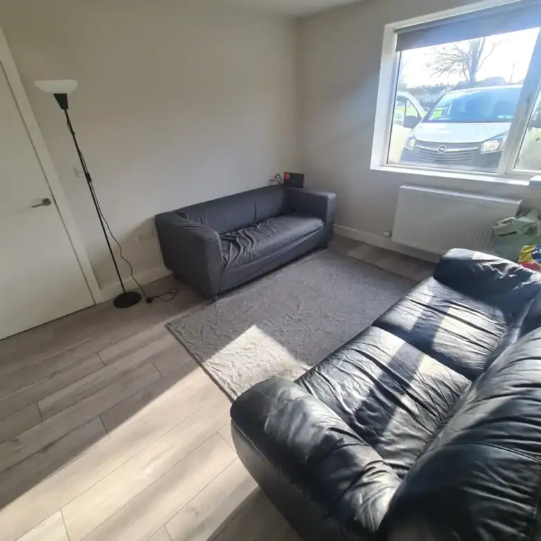 Living room with gray and black leather sofas, rug, and window.