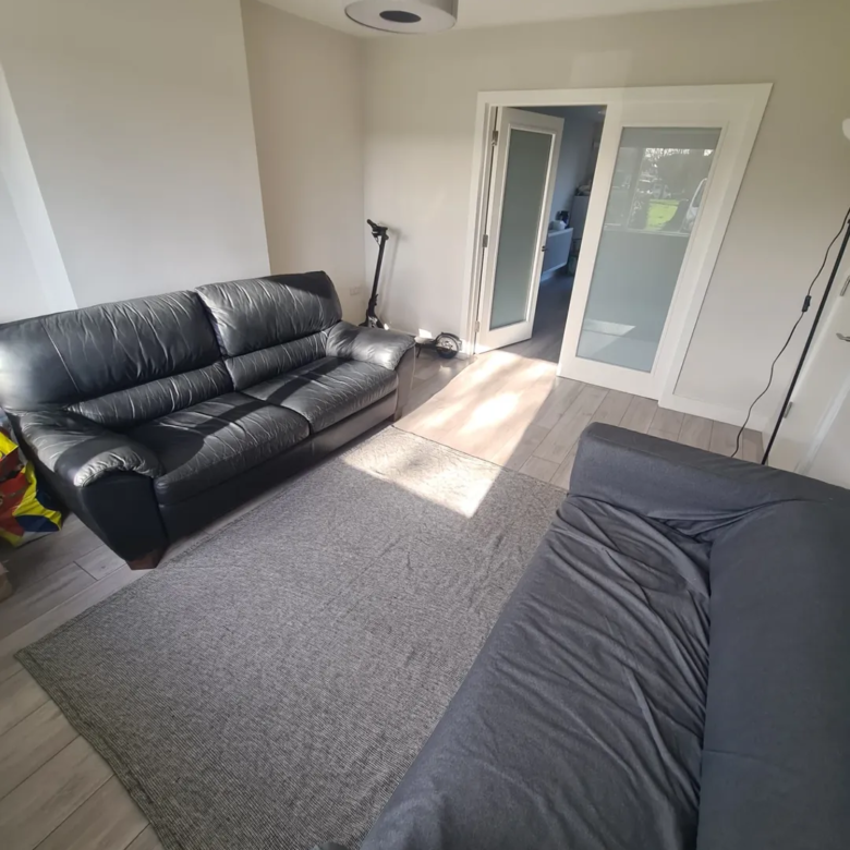 Living room with gray rug, black leather sofa, and gray sofa.