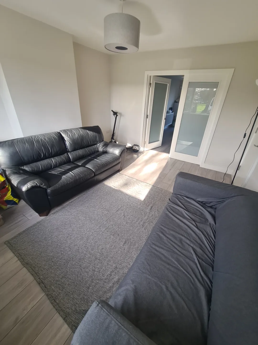 Living room with gray rug, black leather sofa, and gray sofa.