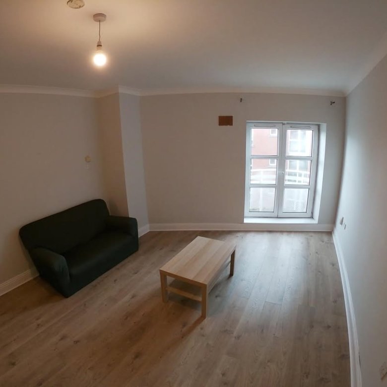 Living room with dark green sofa, light wood coffee table, and large window with natural light.