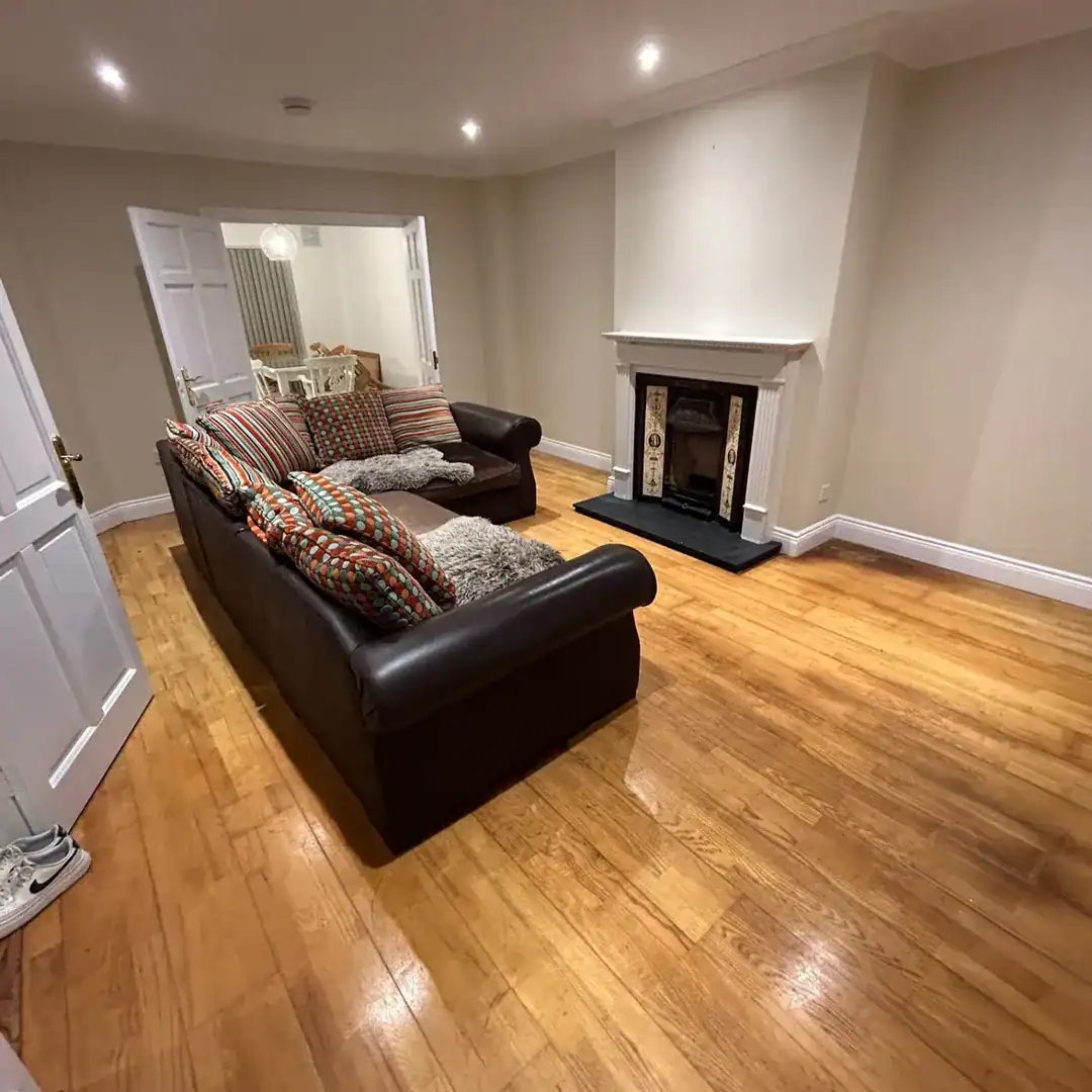 Living room with dark leather sofa and fireplace. Warm wood floors.