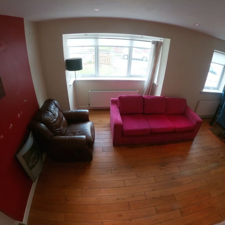 Living room with pink sofa, brown armchair, and blue chairs by window.
