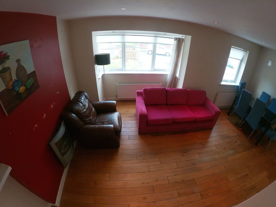 Living room with pink sofa, brown armchair, and blue chairs by window.