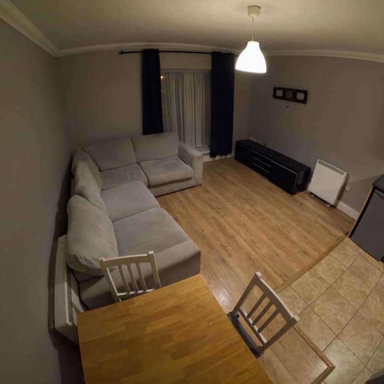 Living room with sectional sofa, dining table, and kitchen area.