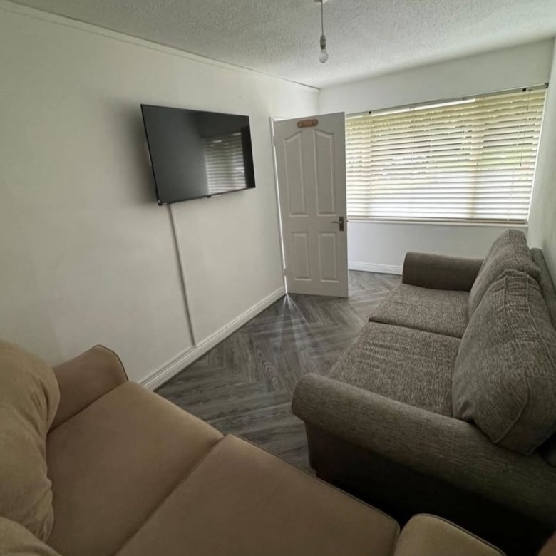 Living room with sofas, TV, and window blinds.