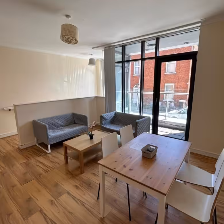 Living room with sofas, wood table, and balcony window.