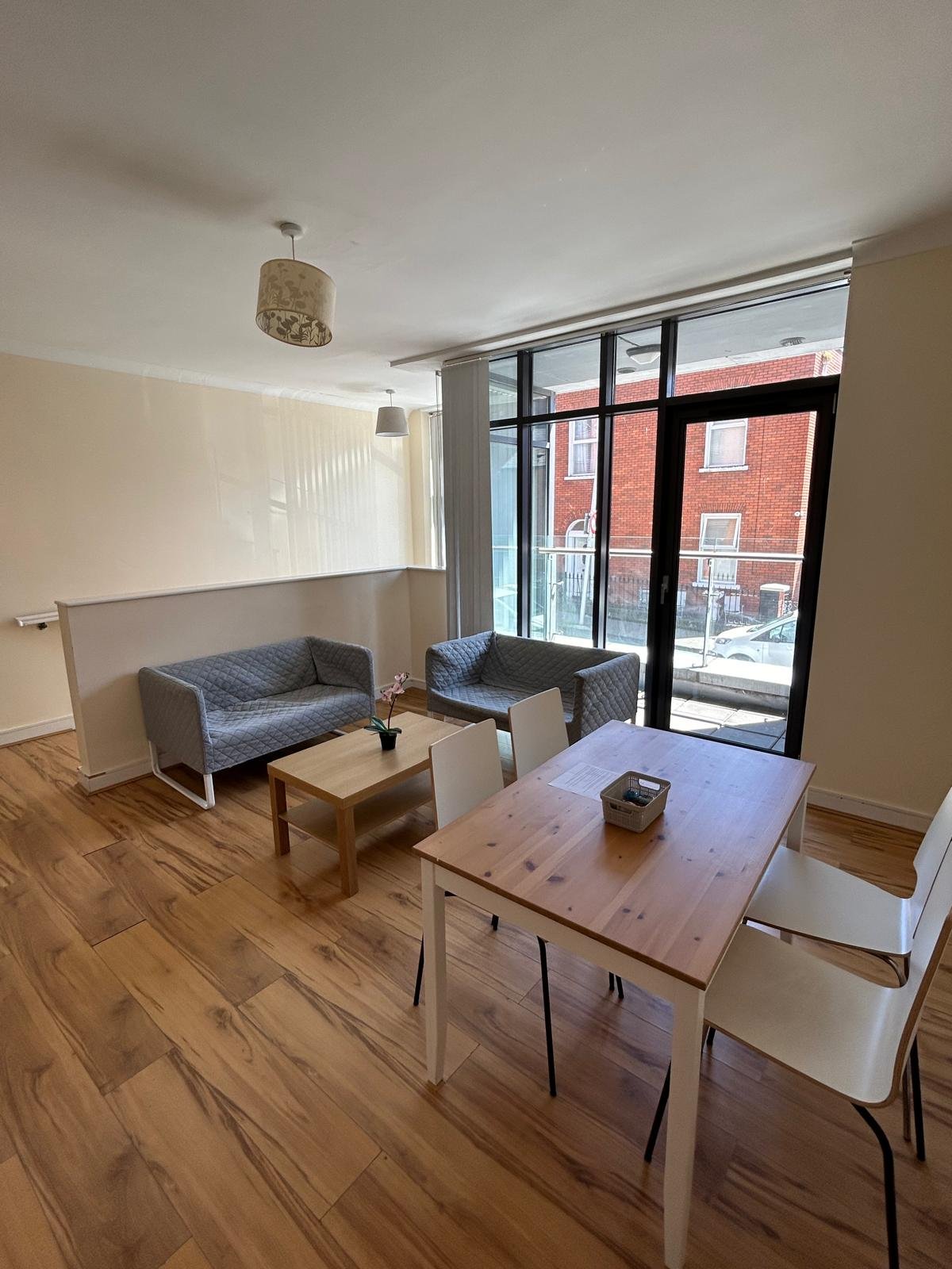 Living room with sofas, wood table, and balcony window.