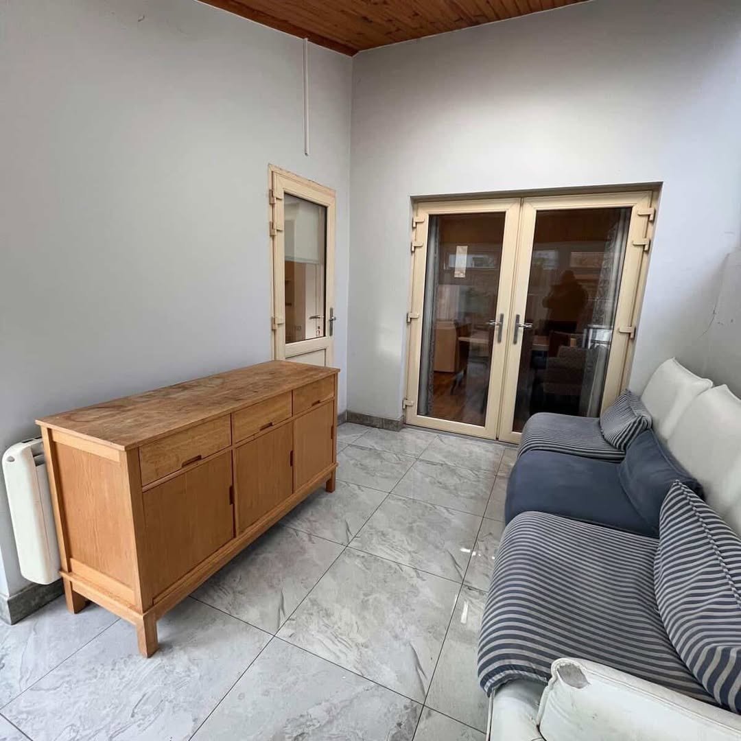 Living room interior with wood cabinet, sofa, and glass doors.