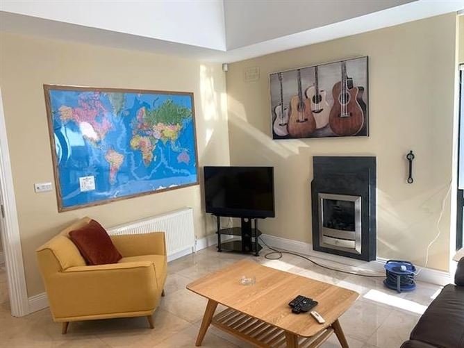 Living room with world map, guitars art, yellow chair, and TV.