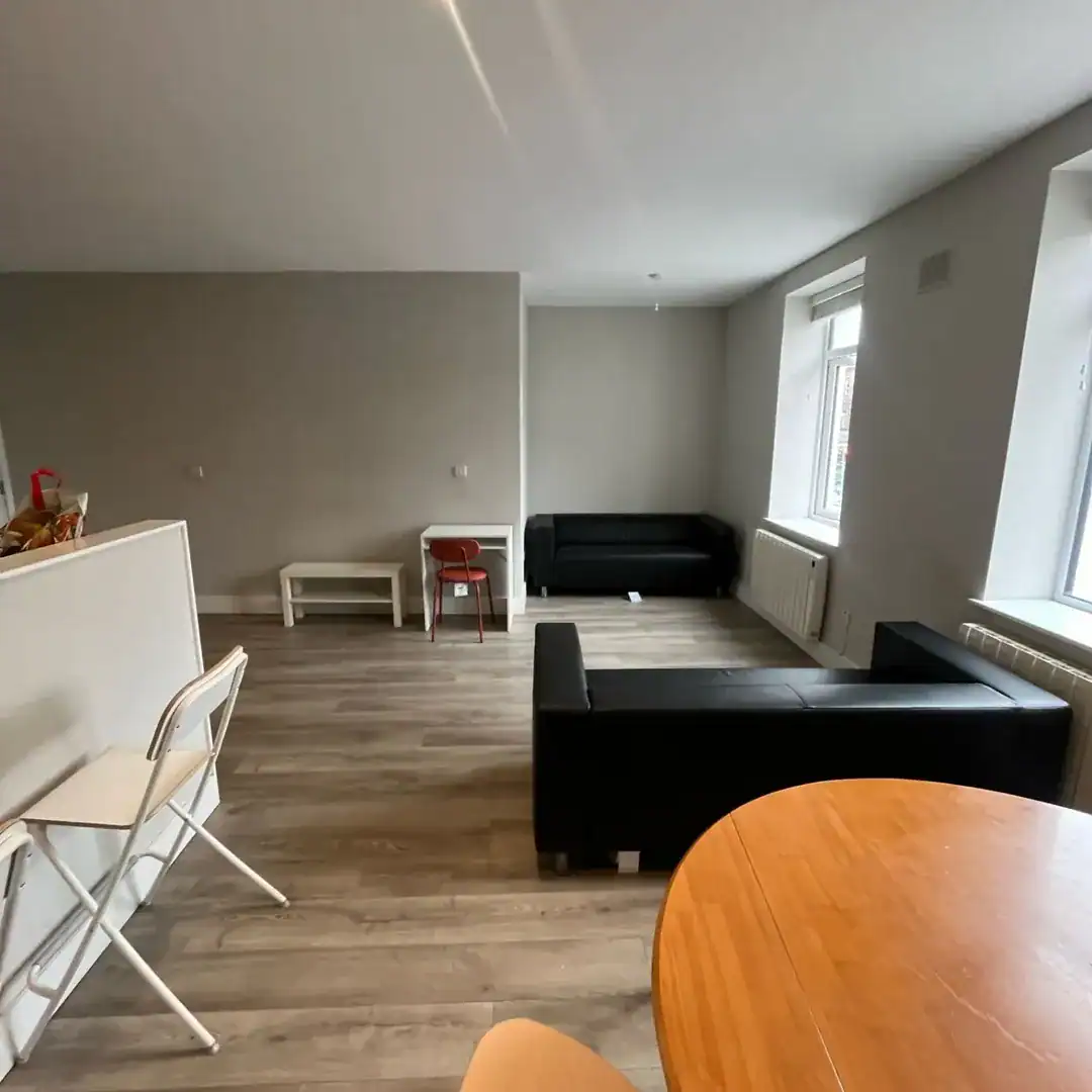 Modern apartment living room with sofas, table, and natural light.