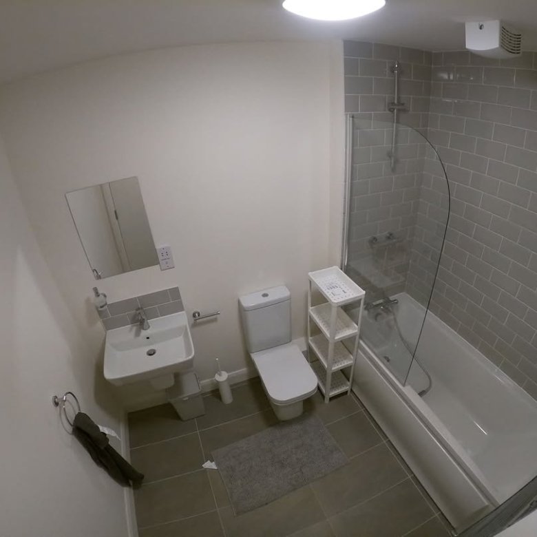 Modern bathroom interior with toilet, sink, bathtub, and gray tile.