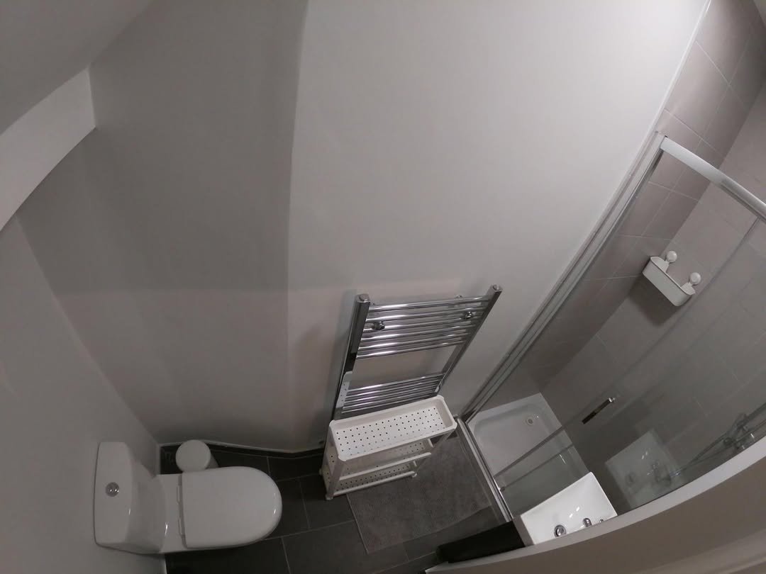 Modern bathroom with toilet, towel rack, and shower stall. Gray and white color scheme.