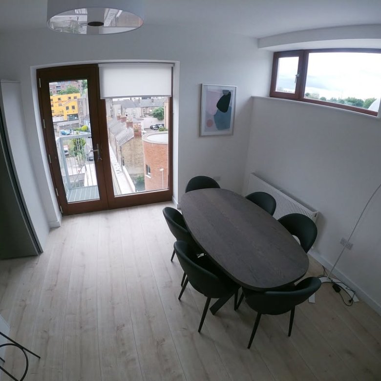 Modern dining area with oval table, chairs, and balcony access.