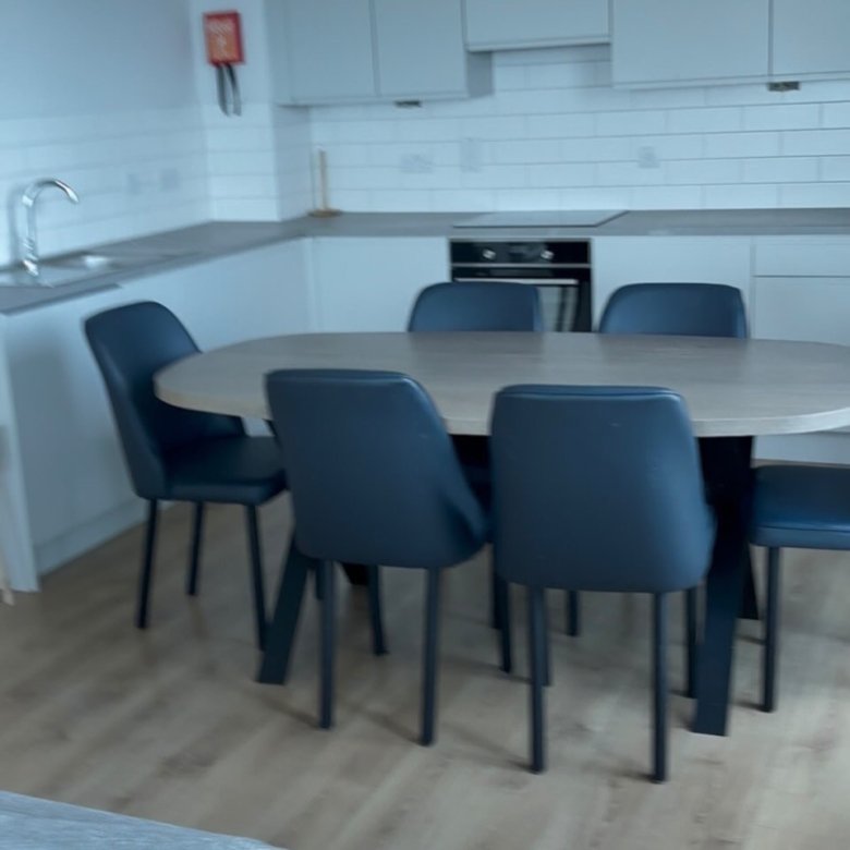 Dining area with oval table and blue chairs in modern kitchen.