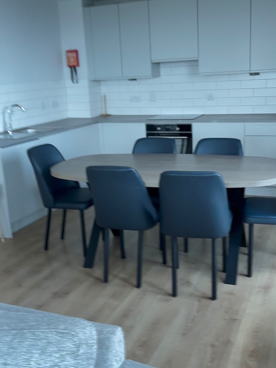 Dining area with oval table and blue chairs in modern kitchen.