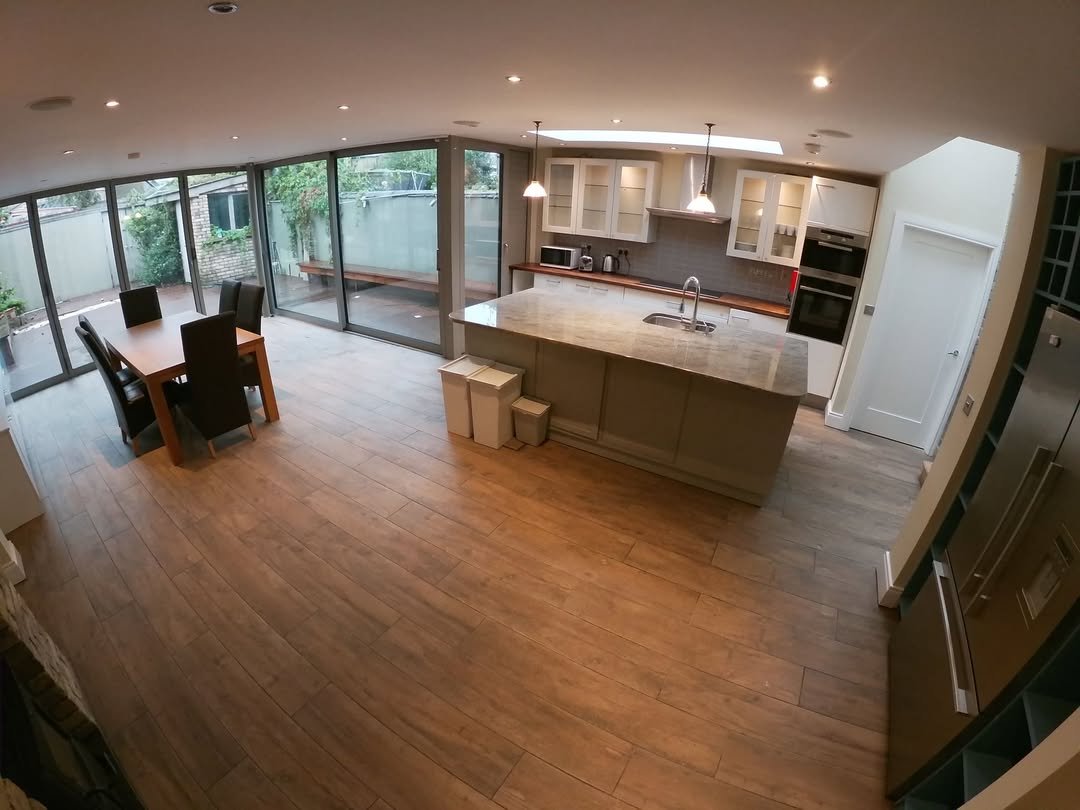 Spacious modern kitchen with island, dining area, and garden view.
