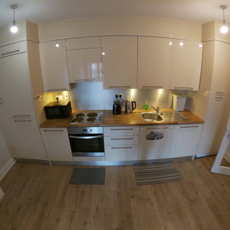 Modern kitchen with light wood cabinets, steel backsplash, and wood-look flooring.