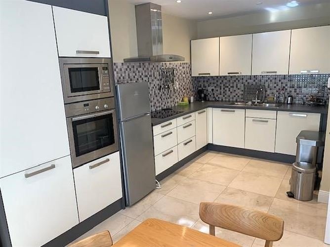 Modern kitchen with white cabinets, stainless steel appliances, and mosaic backsplash.