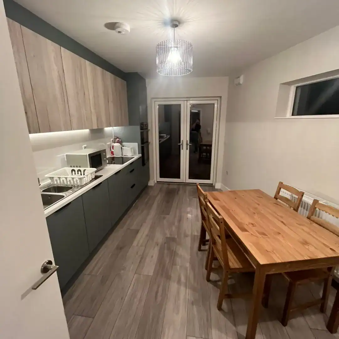 Modern kitchen with wood table, chairs, and gray cabinets.