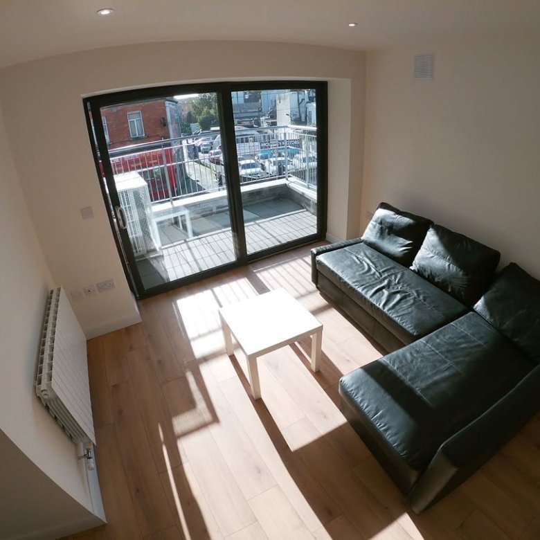Modern living room with black sofa, white table, and balcony doors.