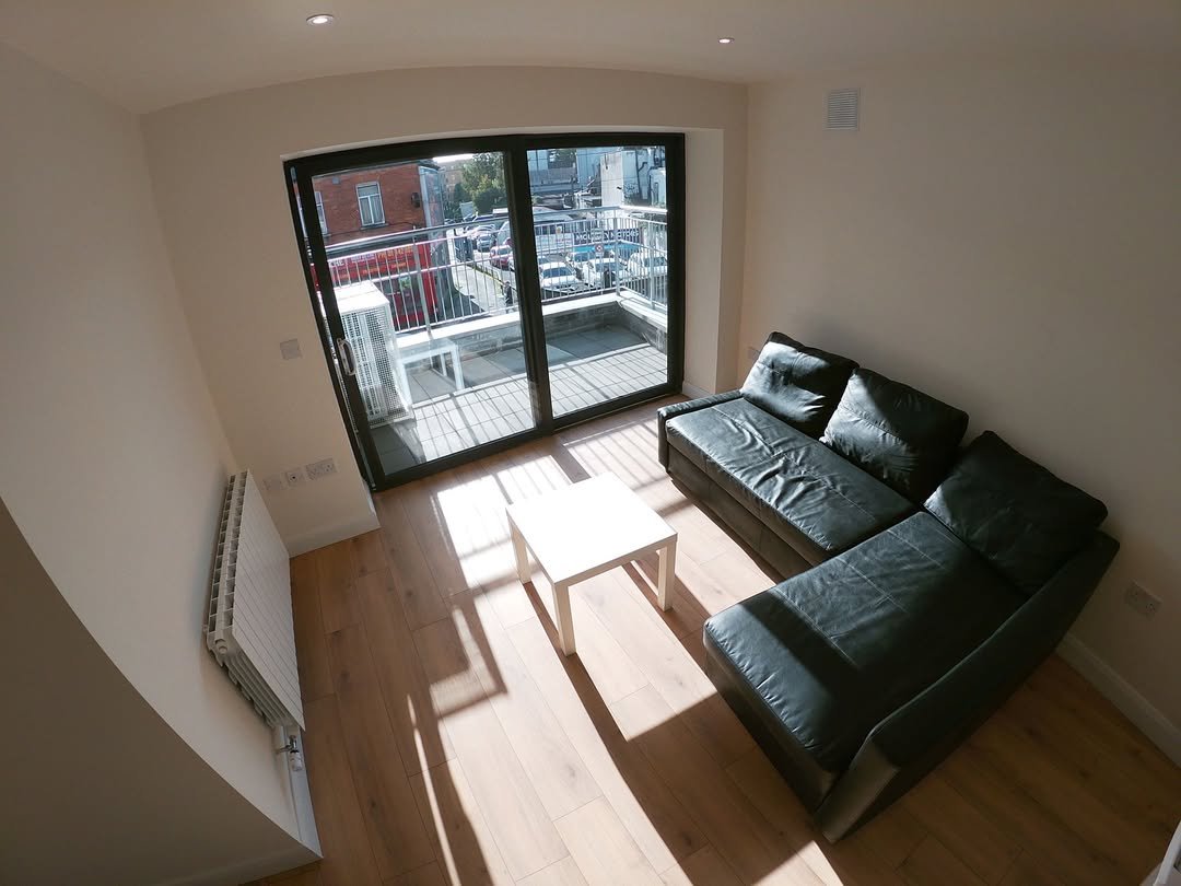 Modern living room with black sofa, white table, and balcony doors.