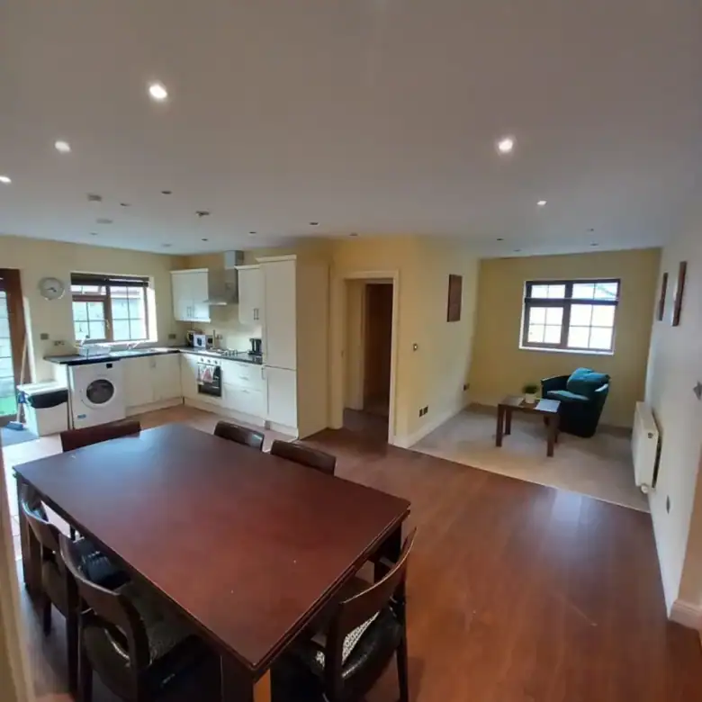 Open-plan kitchen and dining area with wood floors, table, and armchair.