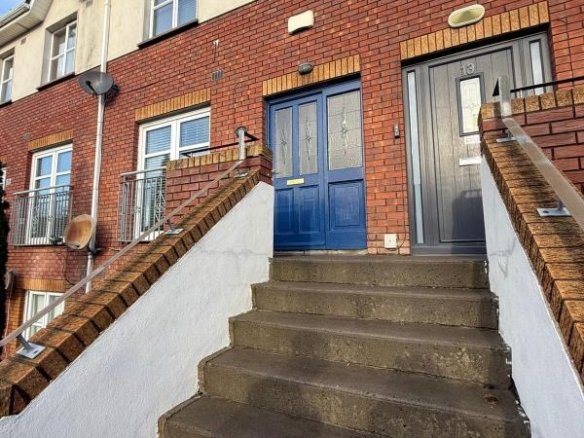 Red brick townhouse with blue door and concrete steps leading to the entrance.