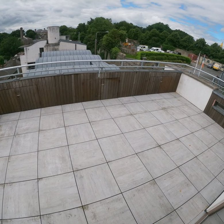 Rooftop terrace with tile flooring, wood paneling, and metal railing.
