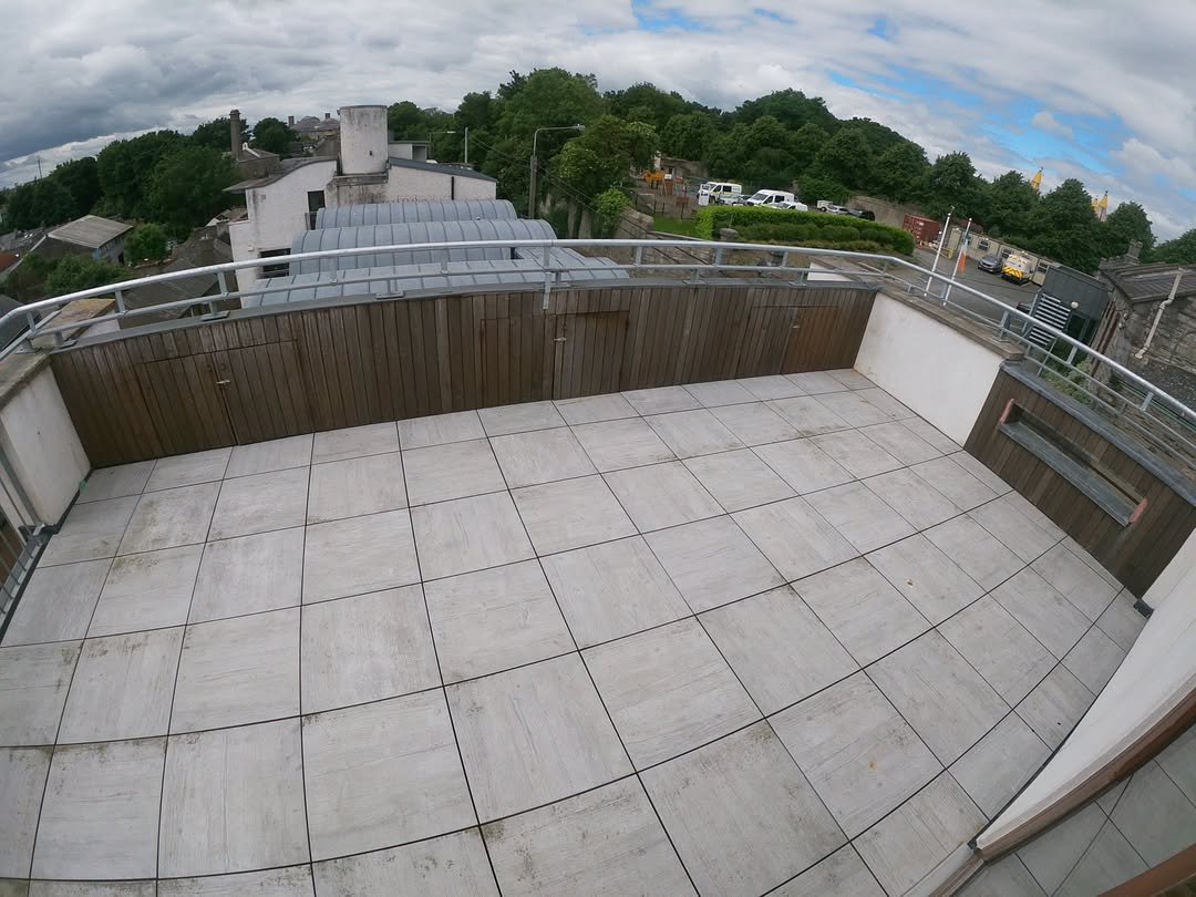 Rooftop terrace with tile flooring, wood paneling, and metal railing.