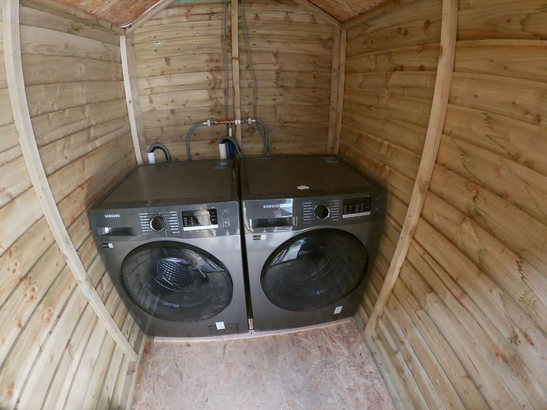 Two Samsung washing machines installed inside a wooden shed.