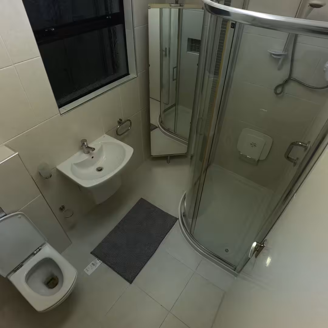Small bathroom with shower, sink, toilet, and mirror. Neutral tile.