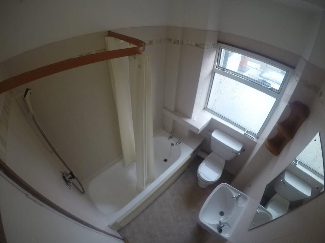 Small bathroom with shower, toilet, sink, and window. Neutral color scheme. Functional design.