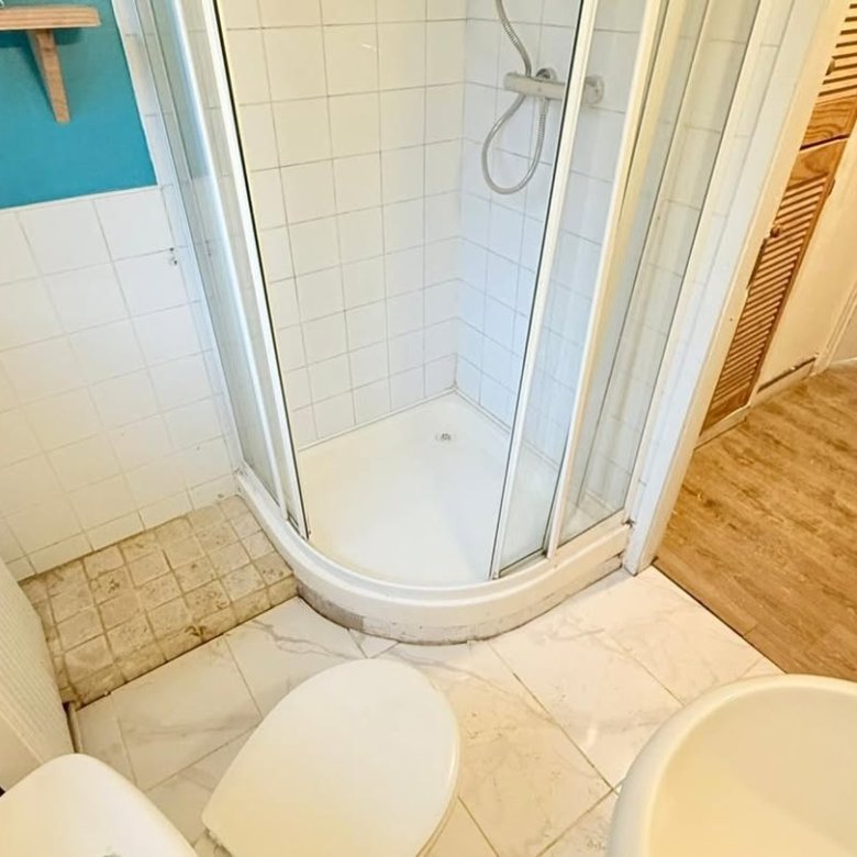 Small bathroom with shower, toilet, sink, and tiling.