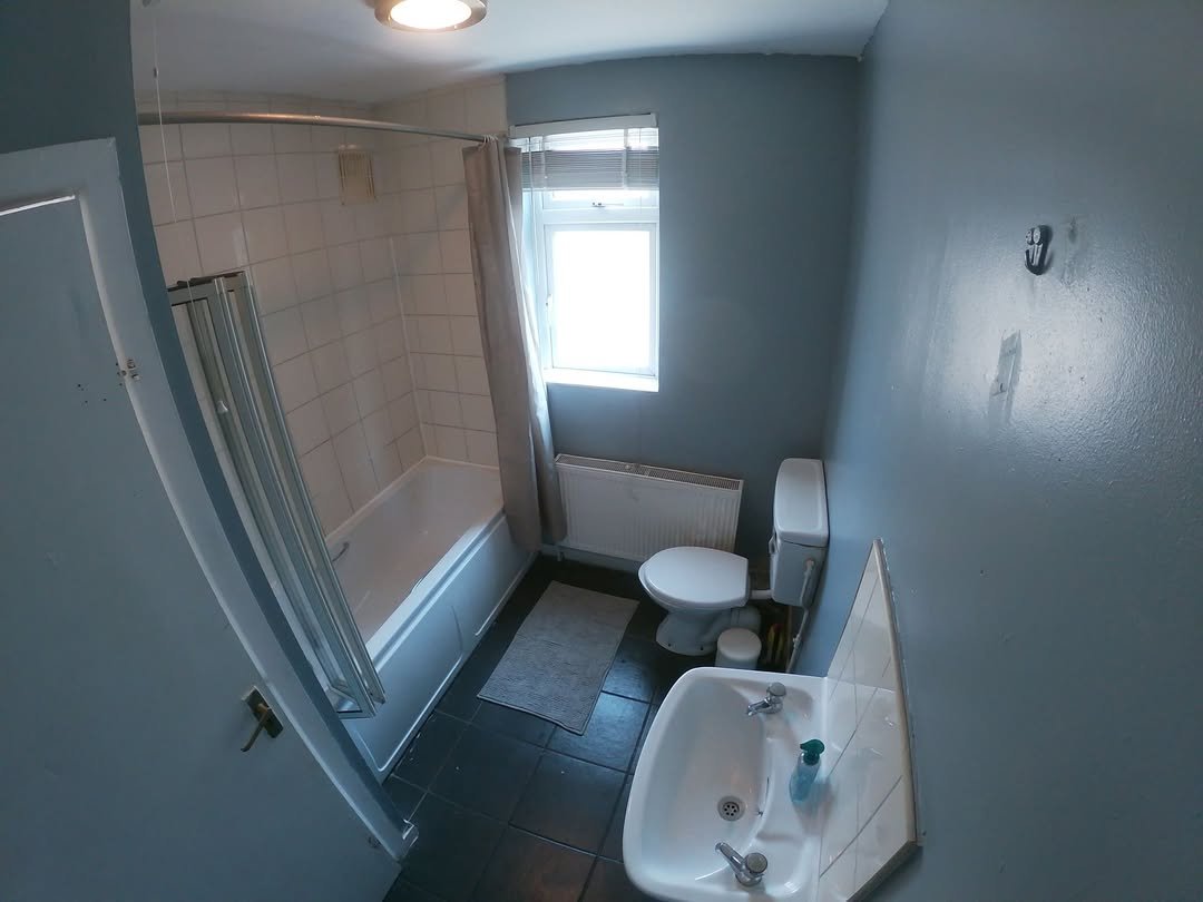 Small bathroom with toilet, sink, and bathtub with shower curtain.