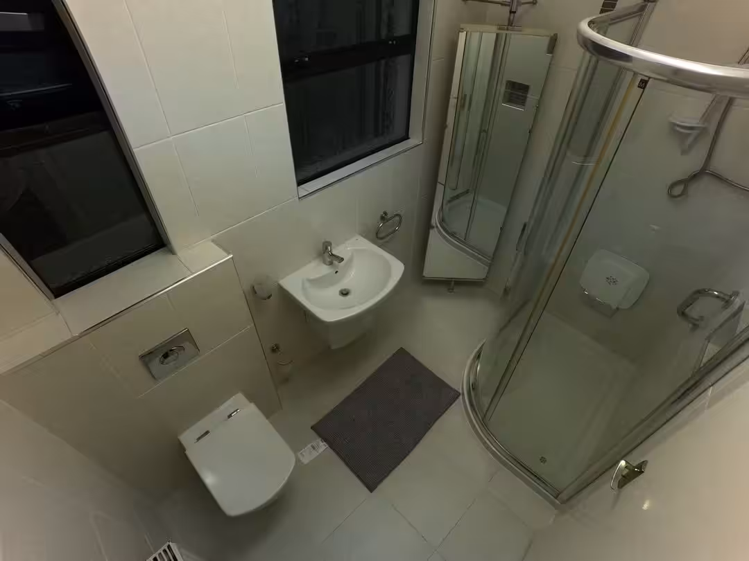 Small bathroom with toilet, sink, shower, and window. Neutral colors.