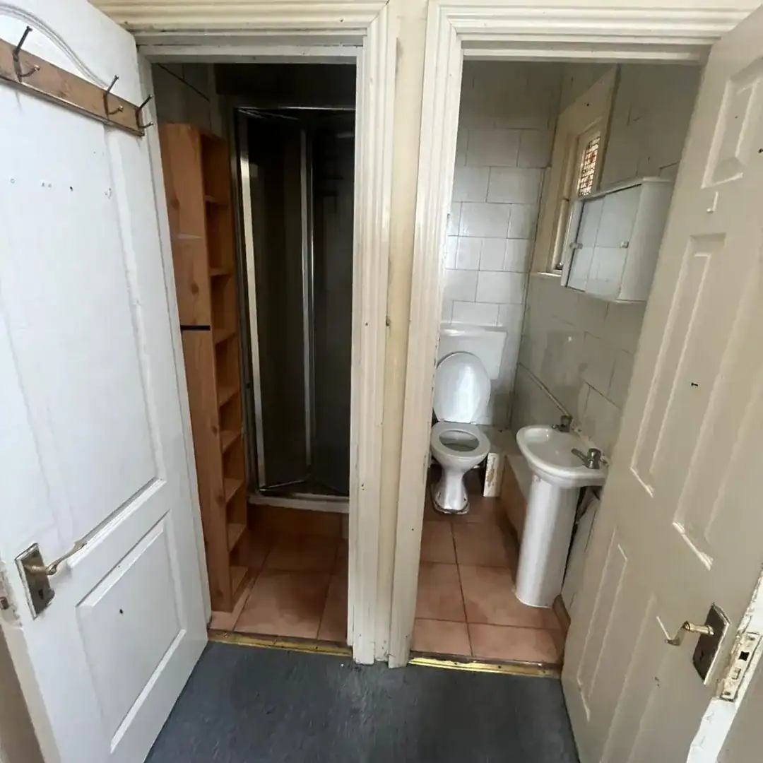 Small bathroom with toilet, sink, and shower stall, white walls.